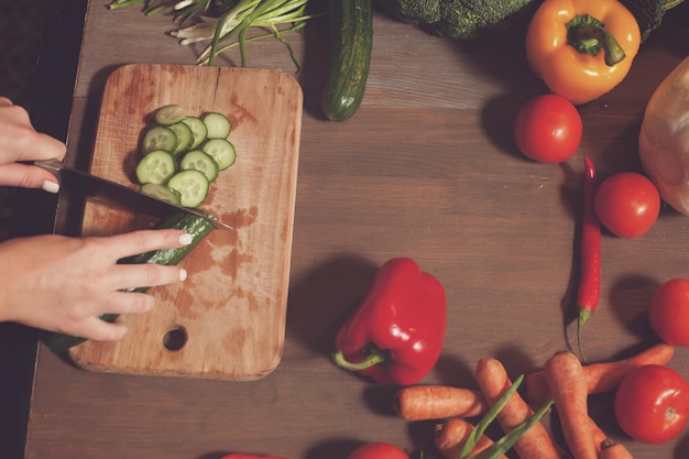 Hands chopping vegetables on wooden board